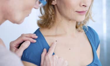 woman patient receives dermatology exam